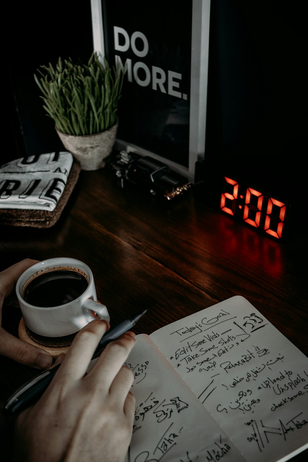 Mãos escrevendo em um diário ao lado de uma xícara de café